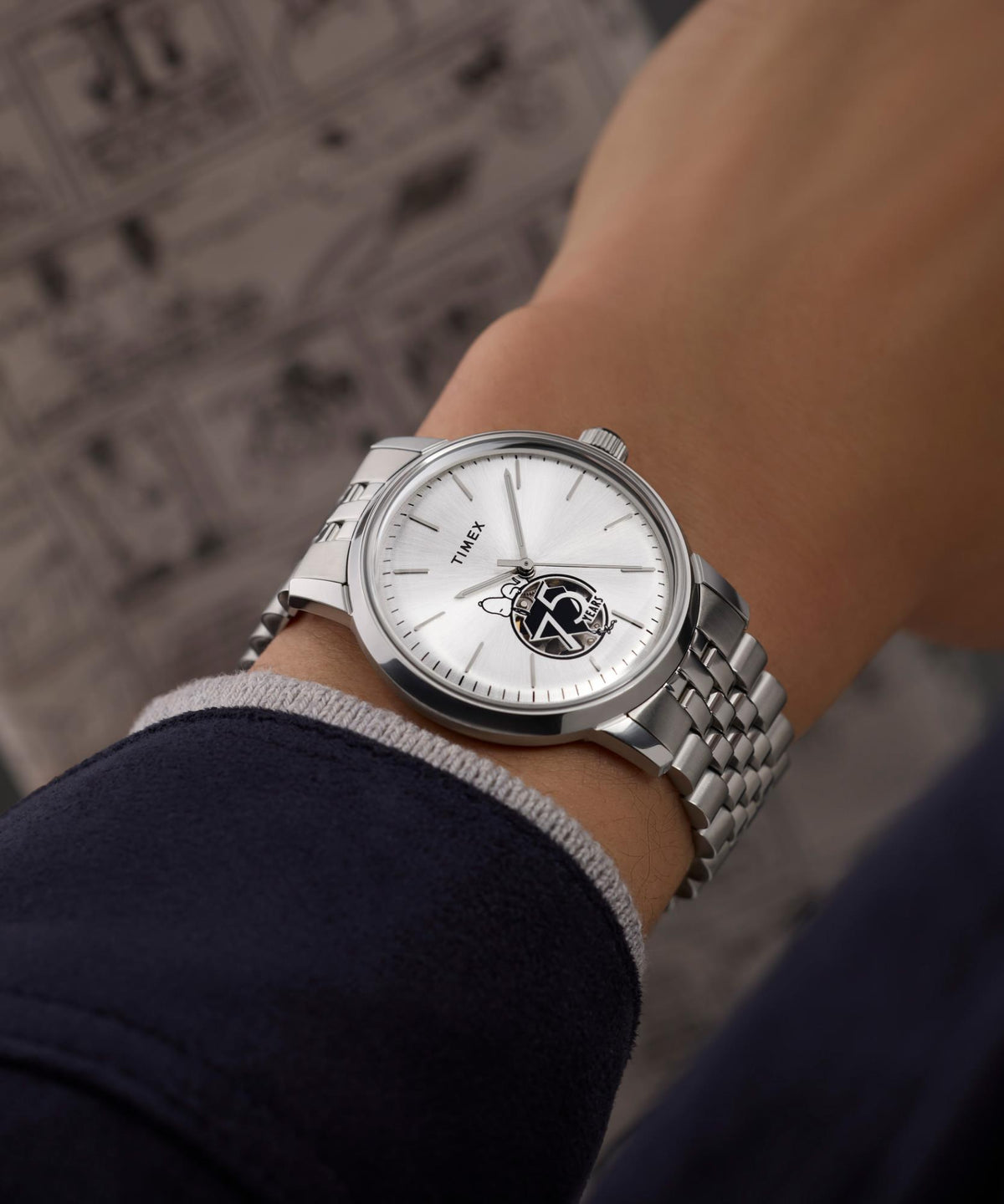 Silver steel wristwatch on arm with white dial and Snoopy 75 Years emblem