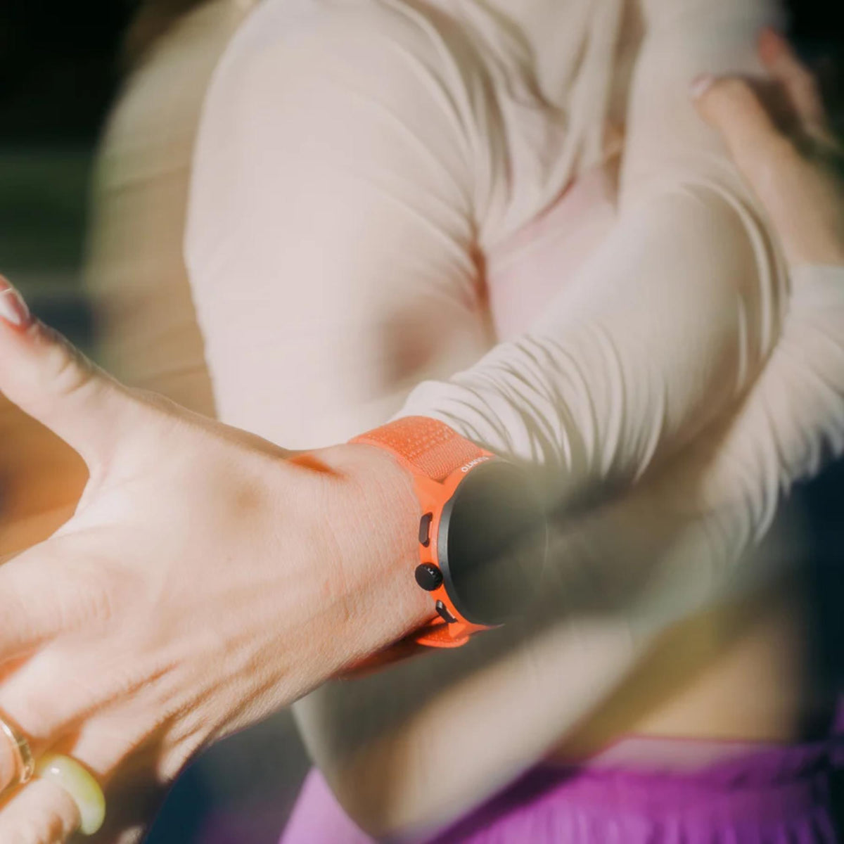Suunto Athletic 7 Loop SS051134000 coral orange textile watch strap action shot worn on wrist during athletic stretching routine