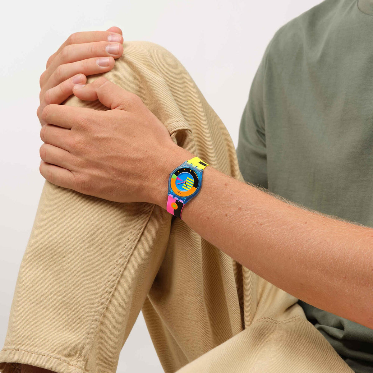 Neon color Swatch watch on wrist with blue dial and multicolor silicone strap