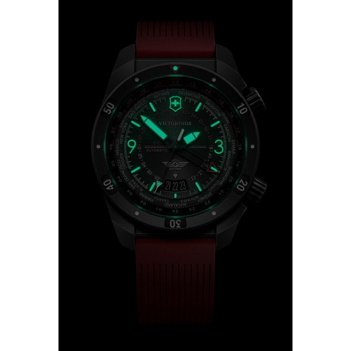 Men's automatic GMT watch in dark view, black case with red strap, green luminous dial