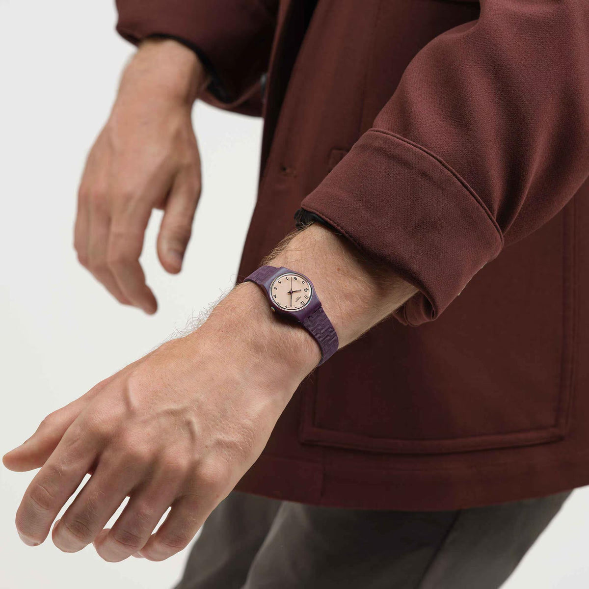Swatch quartz watch with beige dial and dark purple strap on wrist, close-up
