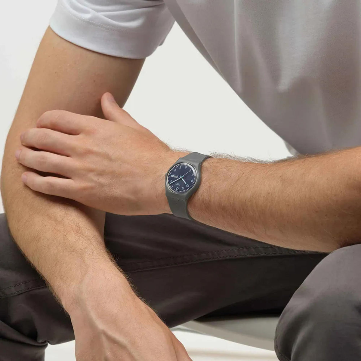 Blue dial quartz watch on wrist with gray silicone strap; analog hands and date window