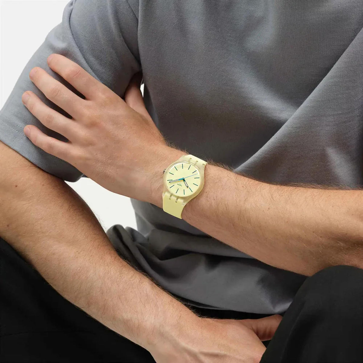 Yellow silicone strap quartz watch on wrist, light yellow dial and teal hands