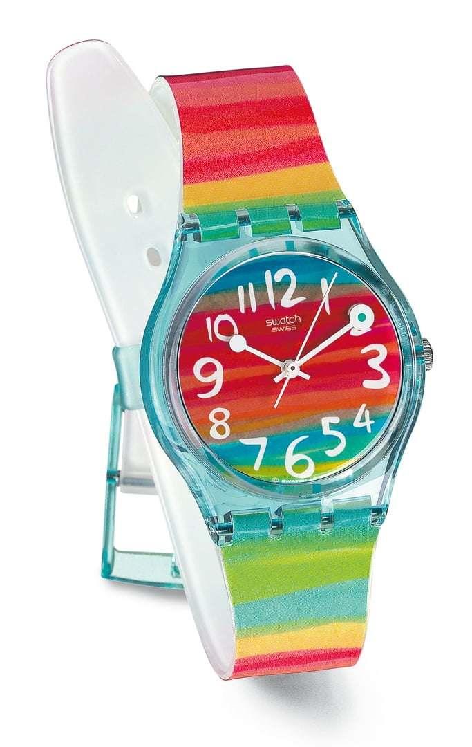 Ladies rainbow stripe analog watch with red dial and multicolor strap on white stand