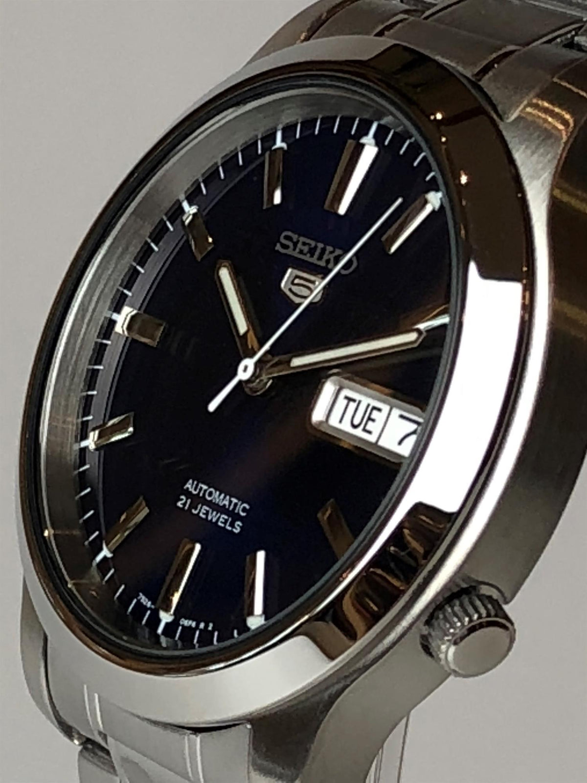 Men's stainless steel automatic watch with dark blue dial, baton hands, and TUE day-date window