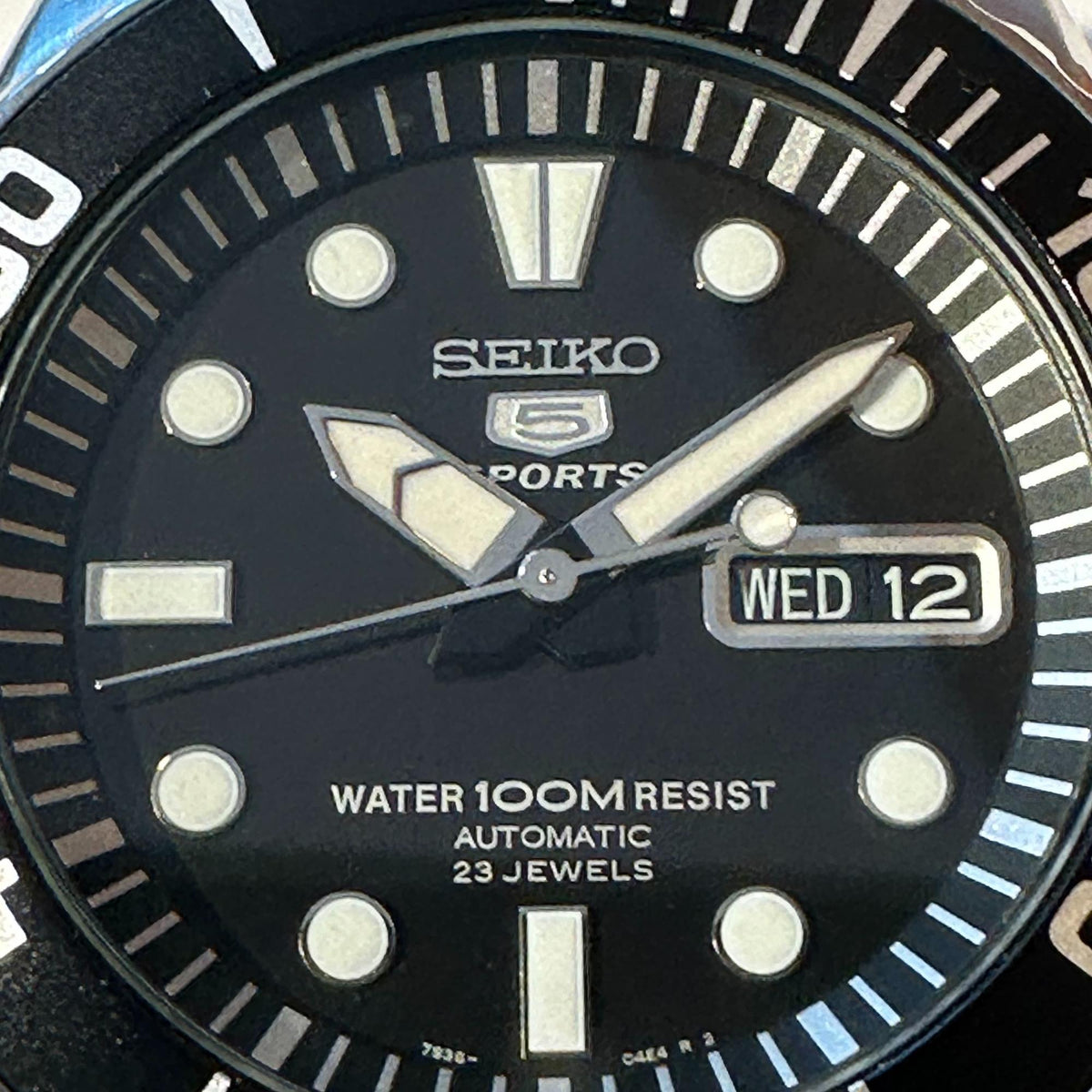 Macro view of black dial automatic men’s watch with Seiko 5 logo and date window
