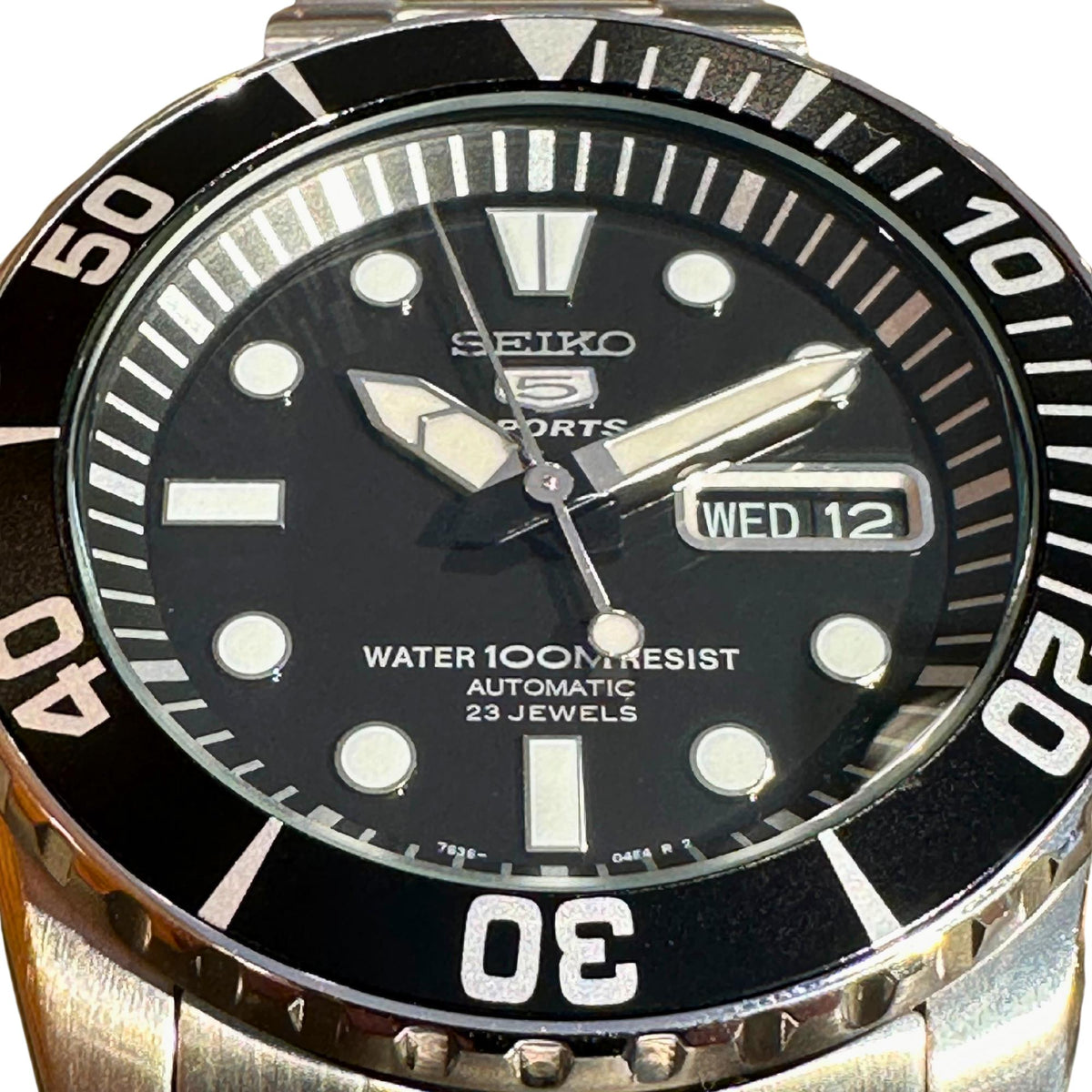 Seiko Sports black dial with silver hands, water resist text, and WED 12 date window