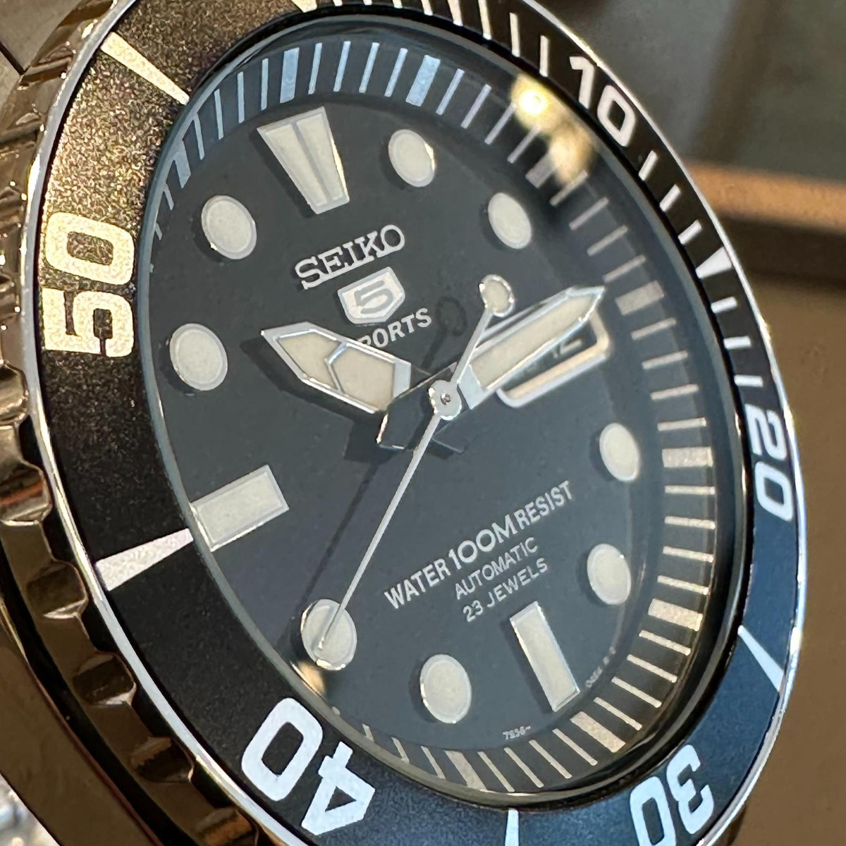 Seiko Sports watch with black dial, luminous dot markers, and bezel showing 50 and 10