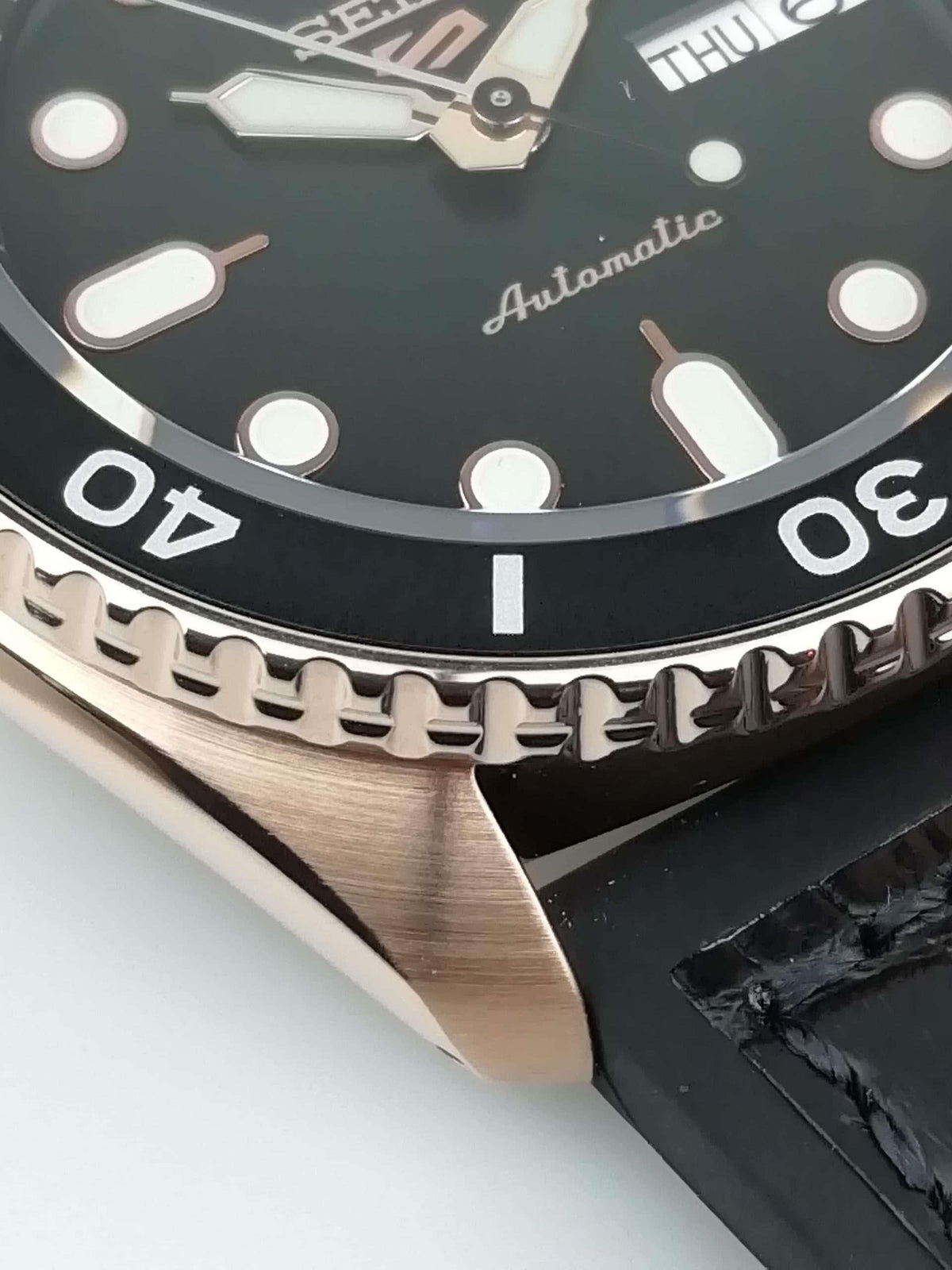 Seiko 5 watch close-up of black dial and bezel with automatic text