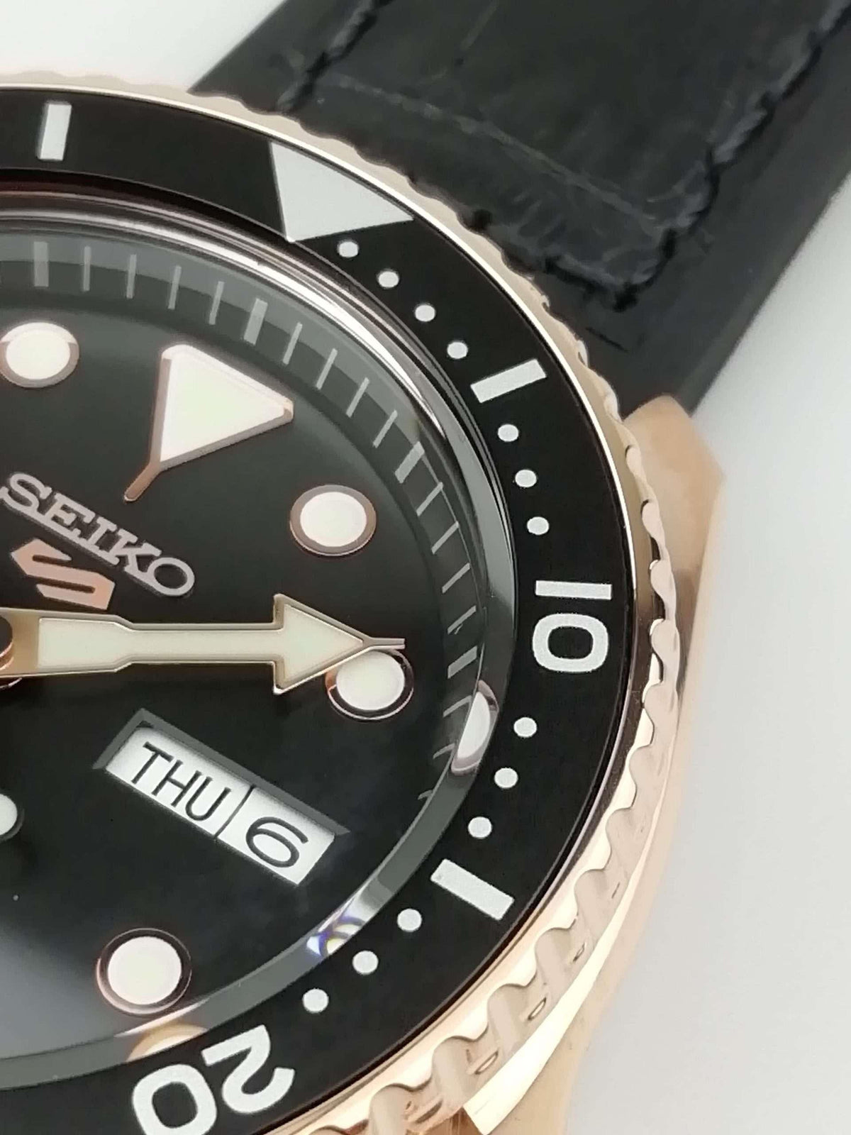 Seiko 5 watch close-up of bezel and black dial with THU 6 date