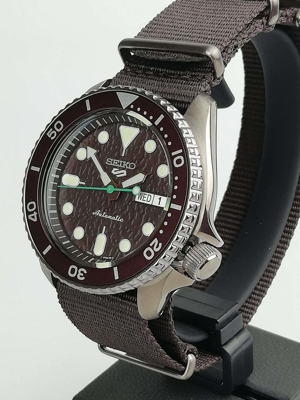 Seiko 5 Sports watch angled view with brown dial, stainless bezel, brown canvas strap
