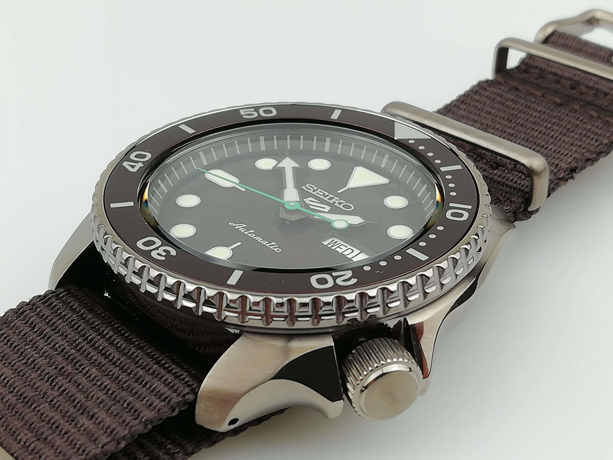Seiko 5 Sports watch side view: stainless case with ridged bezel, brown canvas strap