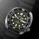 Close-up of green dial diver watch with date window, lumed markers, black bezel