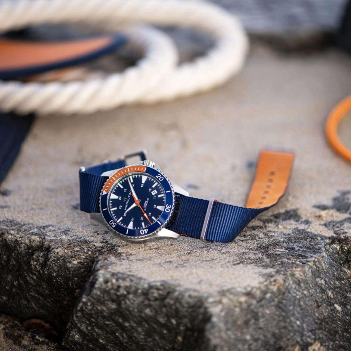 Hamilton automatic watch with blue NATO strap and dark blue dial on textured rock