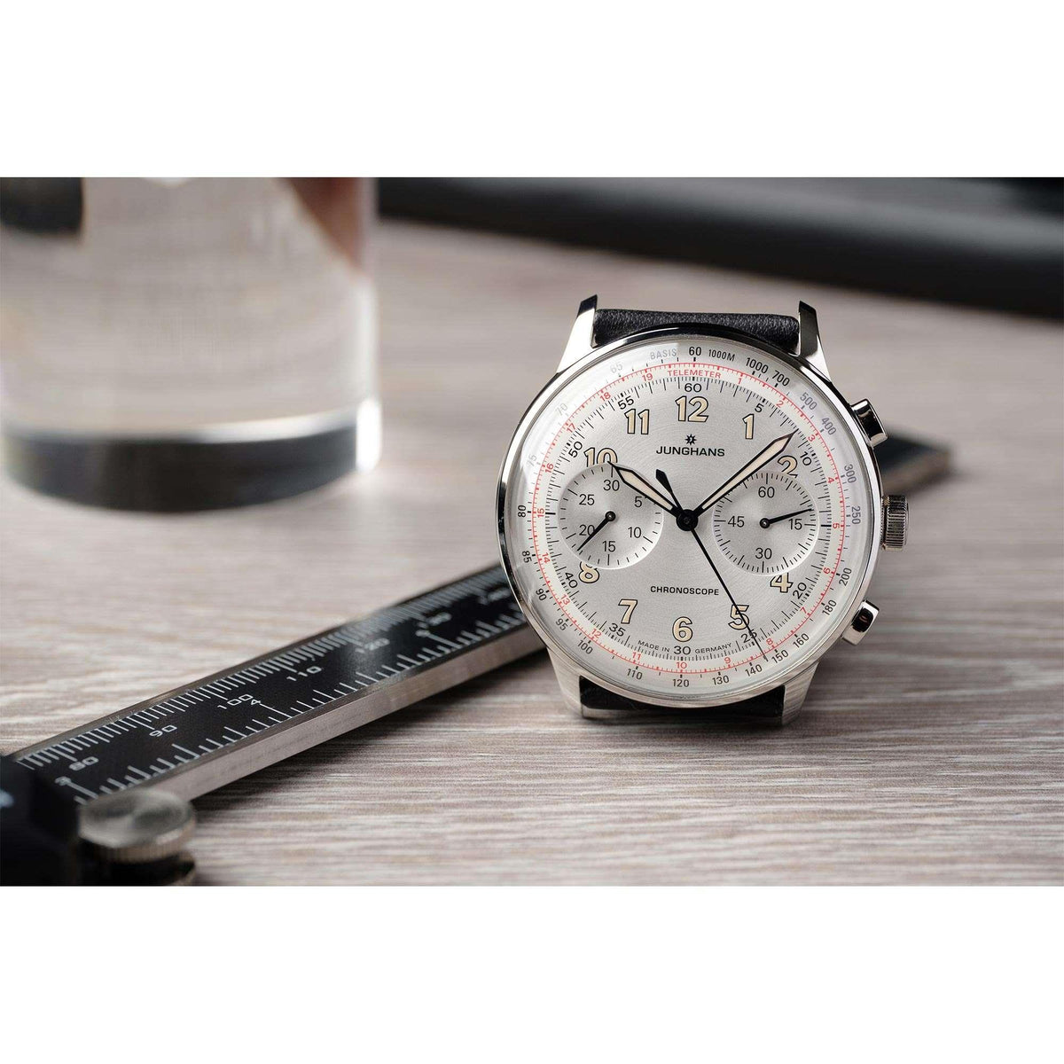 Men's mechanical watch with silver dial, black leather strap, and tachymeter-style markings