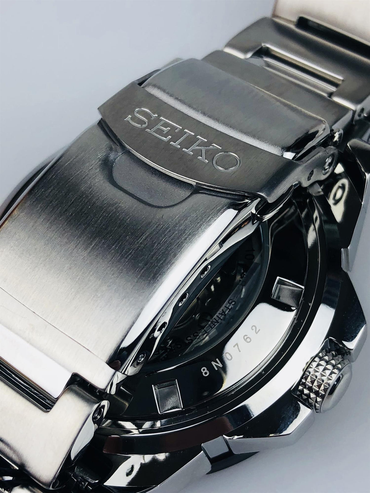 Stainless steel watch bracelet with engraved SEIKO clasp and links, view from side.