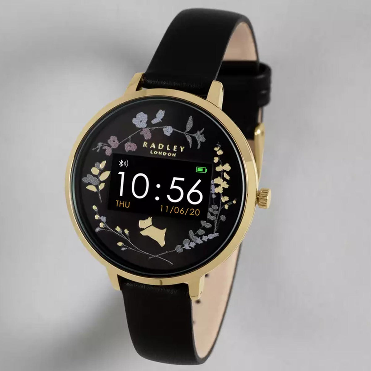 Ladies smartwatch with black leather strap, gold case, floral dial showing 10:56