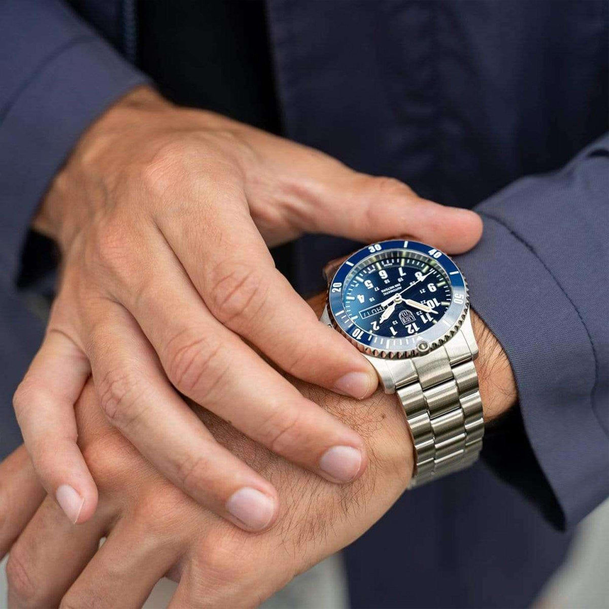 Men's wristwatch on a hand with blue dial and silver stainless steel bracelet