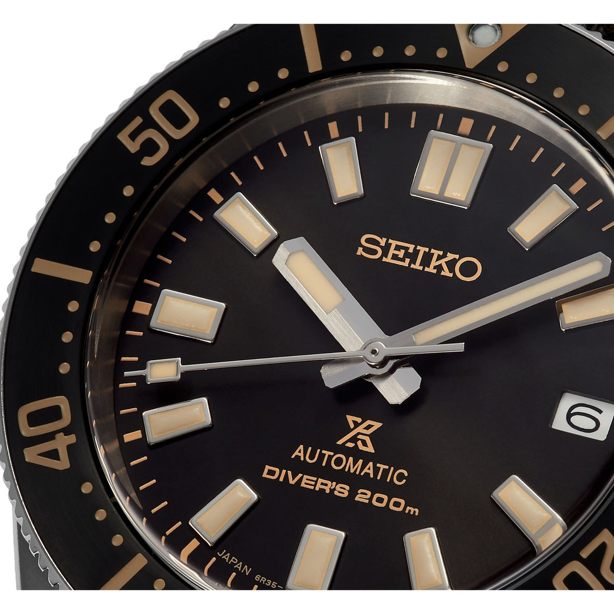 Men's Seiko diver watch dial detail with gold indices, black face, and white hour markers