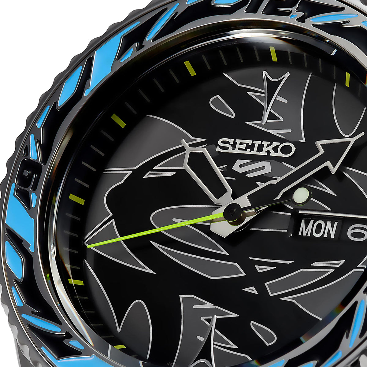 Close-up black dial with Seiko logo, green minute marks, hands, and MON 6 window