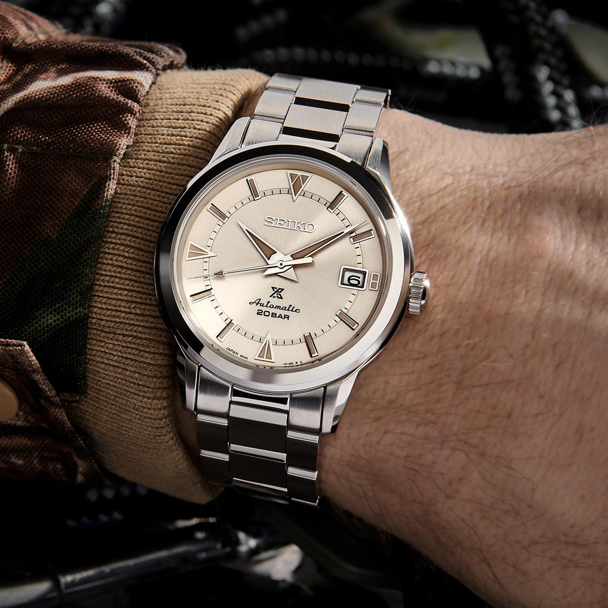 Men's stainless steel automatic watch on wrist, cream dial with date window, metal bracelet