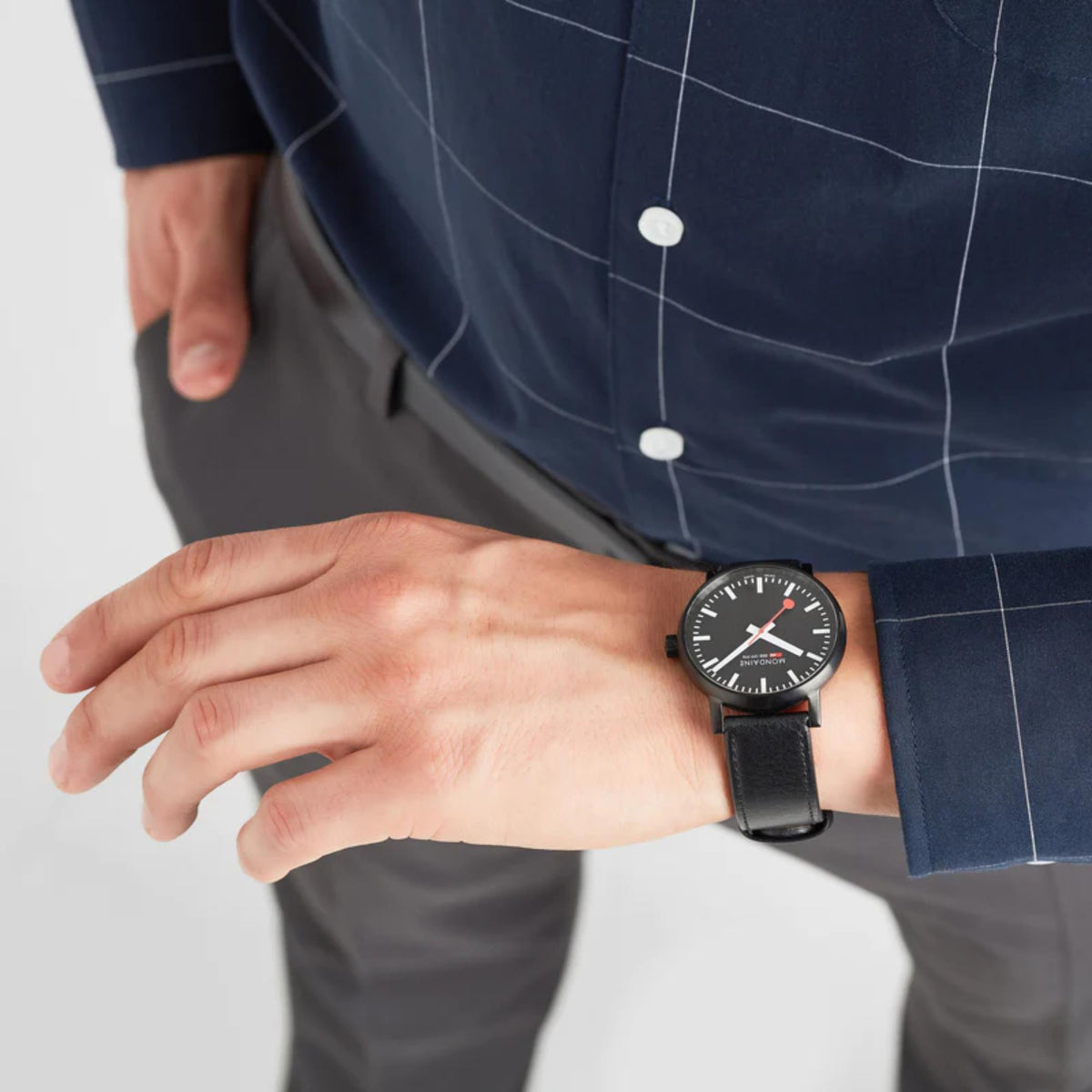 Black leather strap wrist watch with black dial and red hands, worn by a man