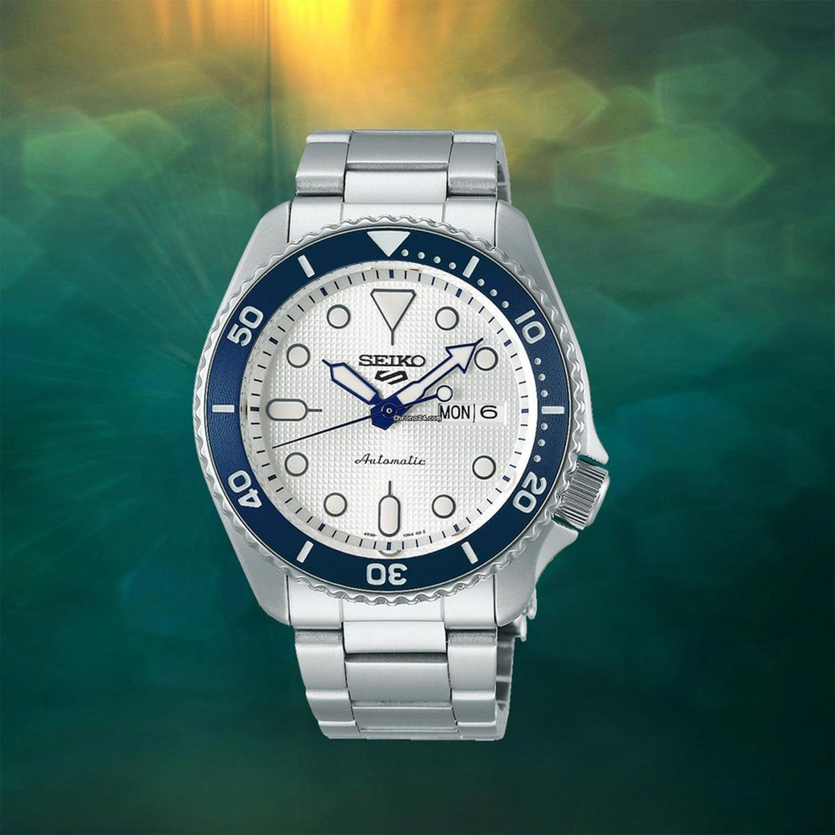 Men's automatic watch with white dial, blue bezel, and stainless steel bracelet