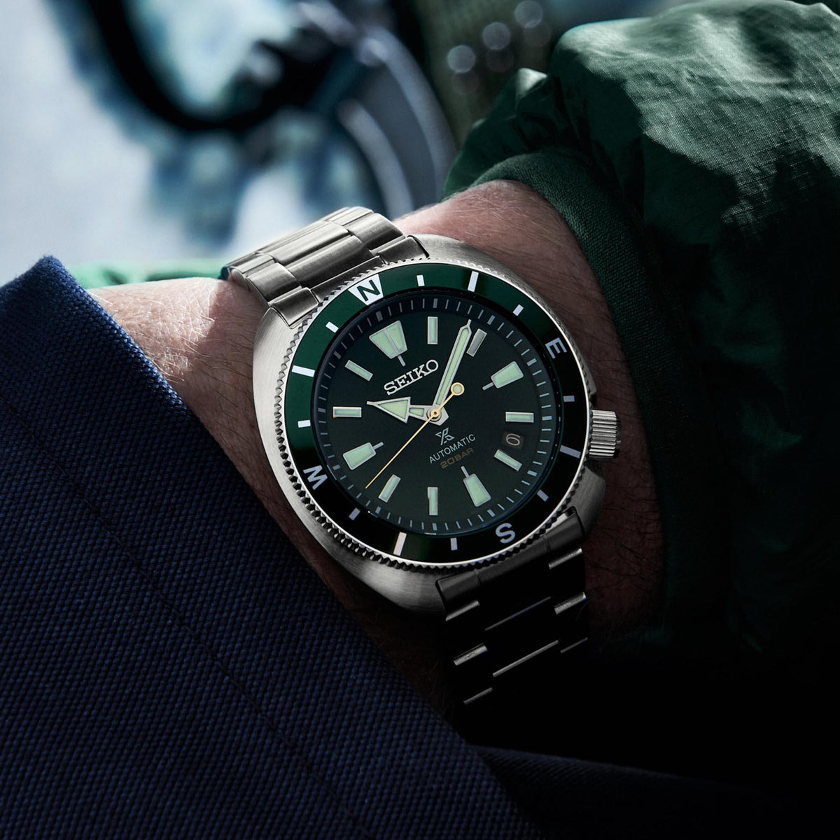 Men's steel automatic watch on wrist, SEIKO green dial and link bracelet, angled close