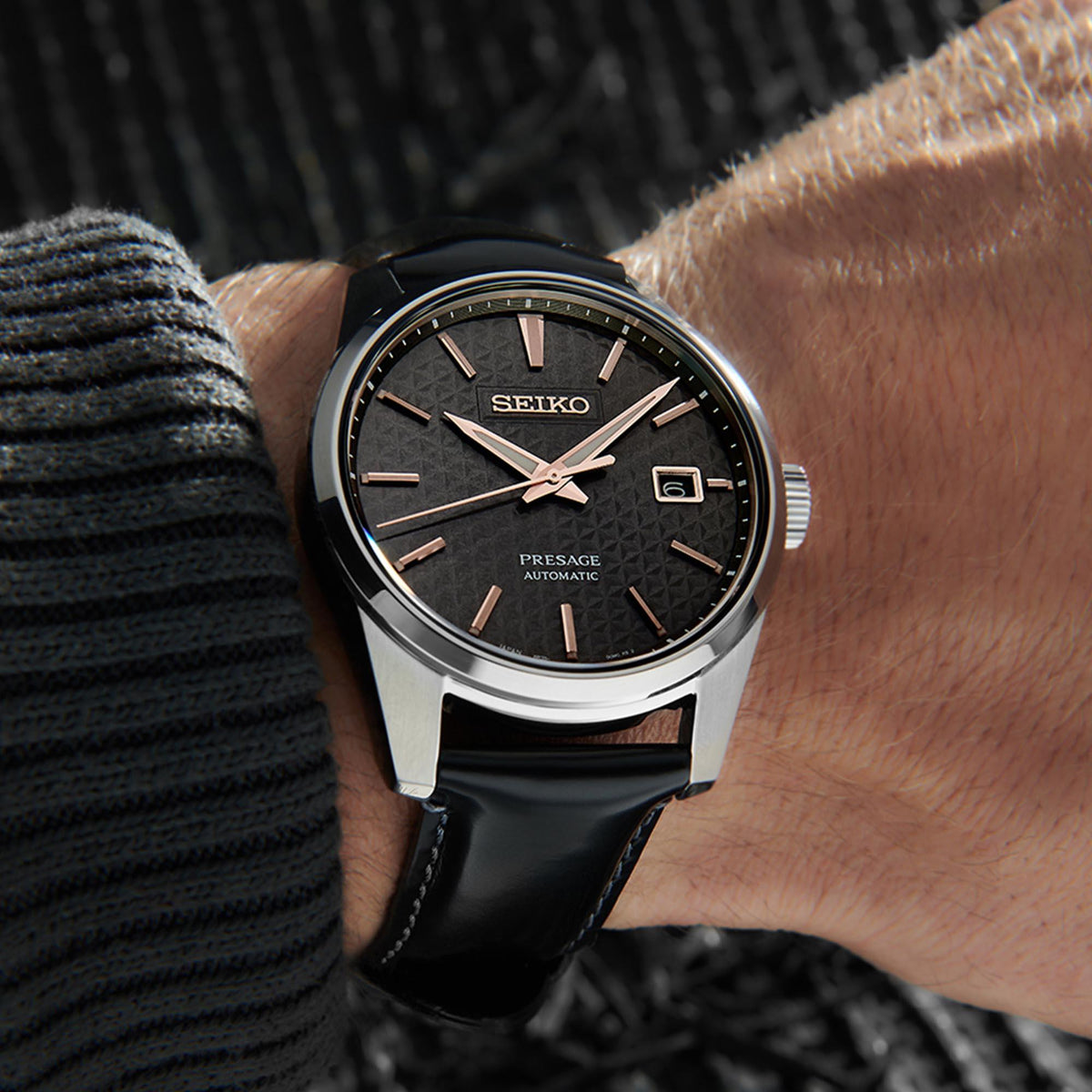 Men's Seiko automatic watch on wrist: black dial with rose-gold markers, leather strap