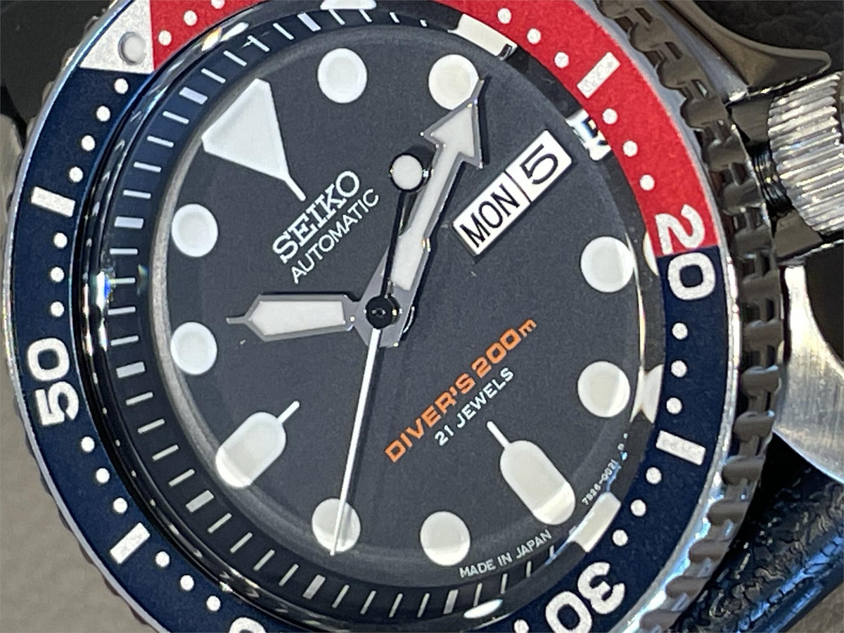 Close-up of the Seiko Diver’s Pepsi blue dial, showcasing the printed "SEIKO AUTOMATIC" text, luminescent indices, and the textured coin-edge bezel.