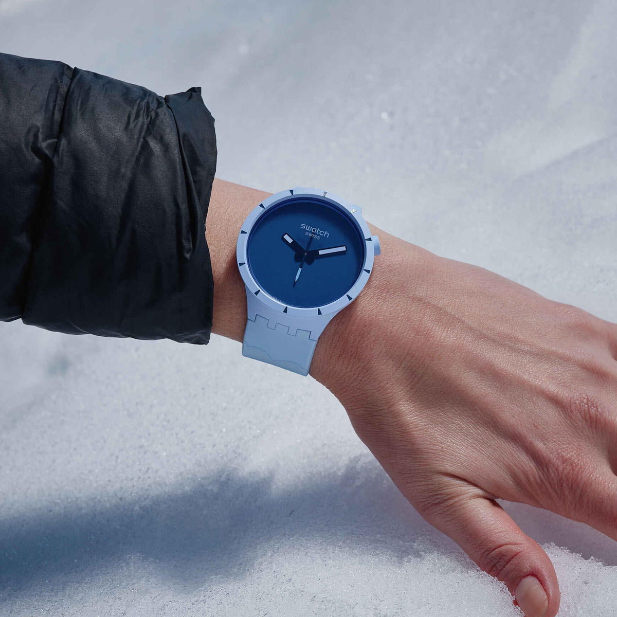 Blue dial watch with light blue silicone strap on wrist in snowy outdoor scene