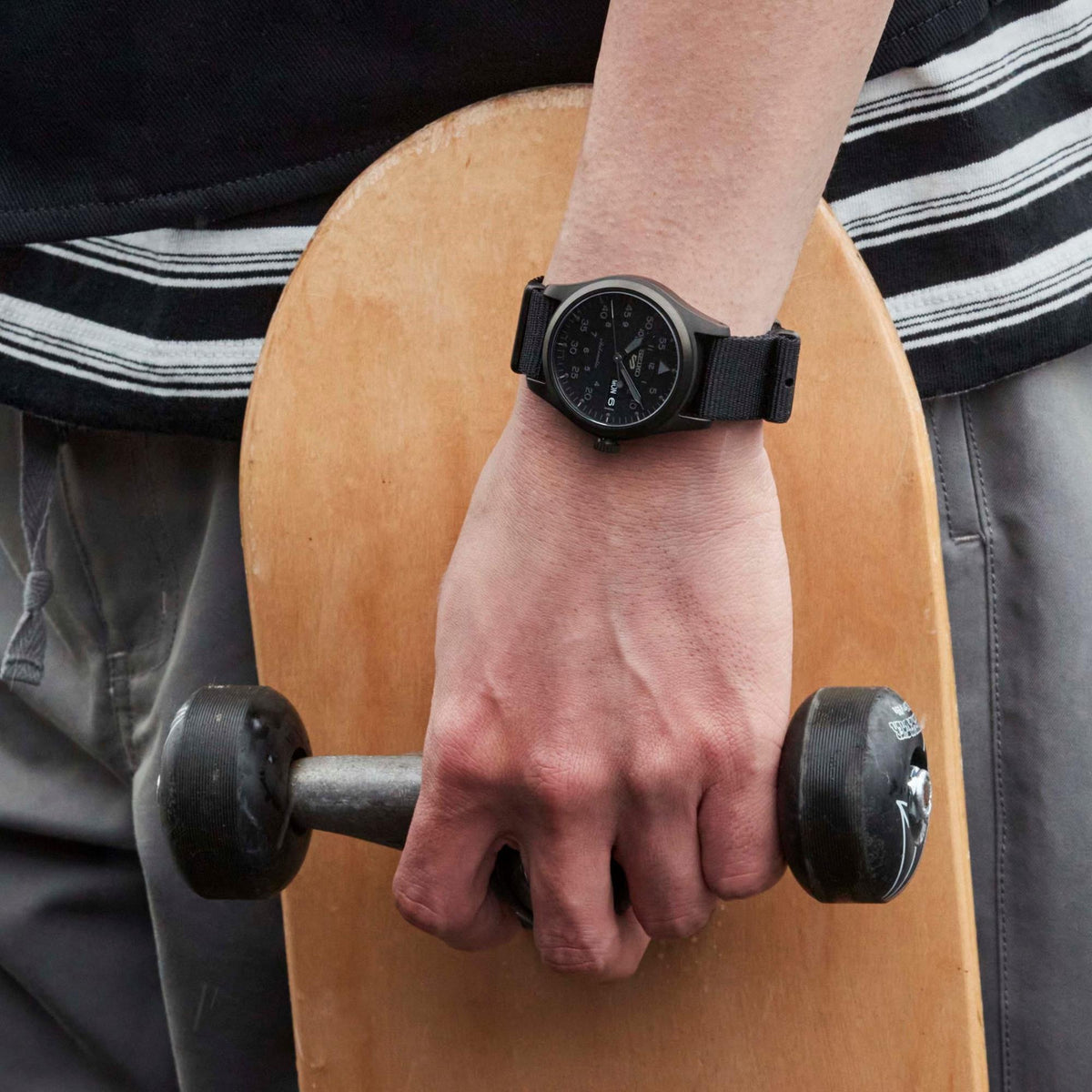 Men's black automatic field watch on wrist with black dial and day-date window