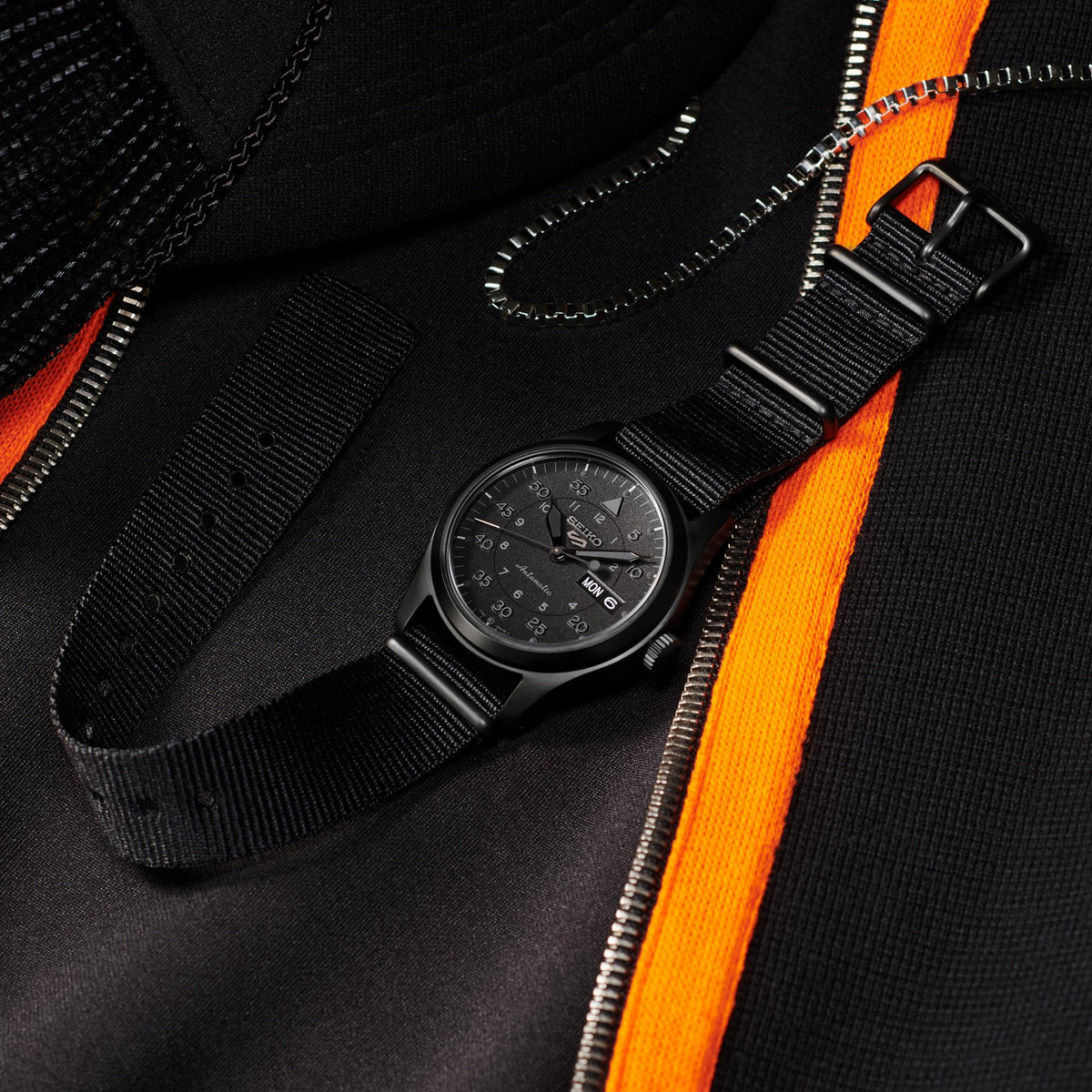 Black automatic field watch with black nylon strap and crown, close-up view