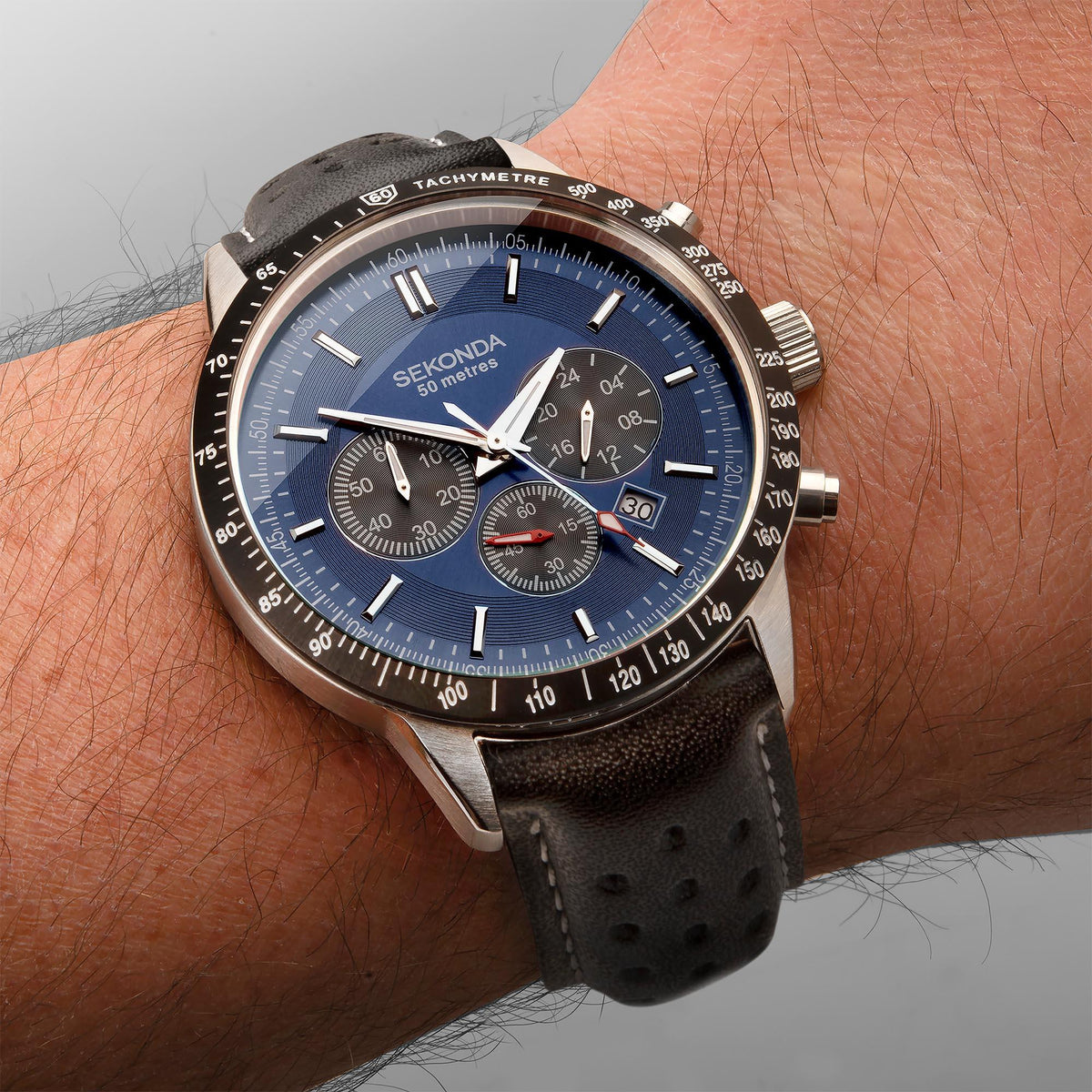 Men's chronograph watch on wrist, dark blue dial with black leather strap