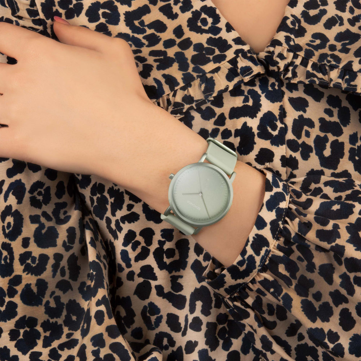 Quartz watch on wrist with light green dial and rubber strap