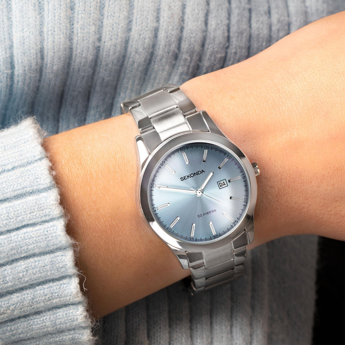 Ladies stainless steel watch worn on wrist, light blue dial with date window and silver bracelet.