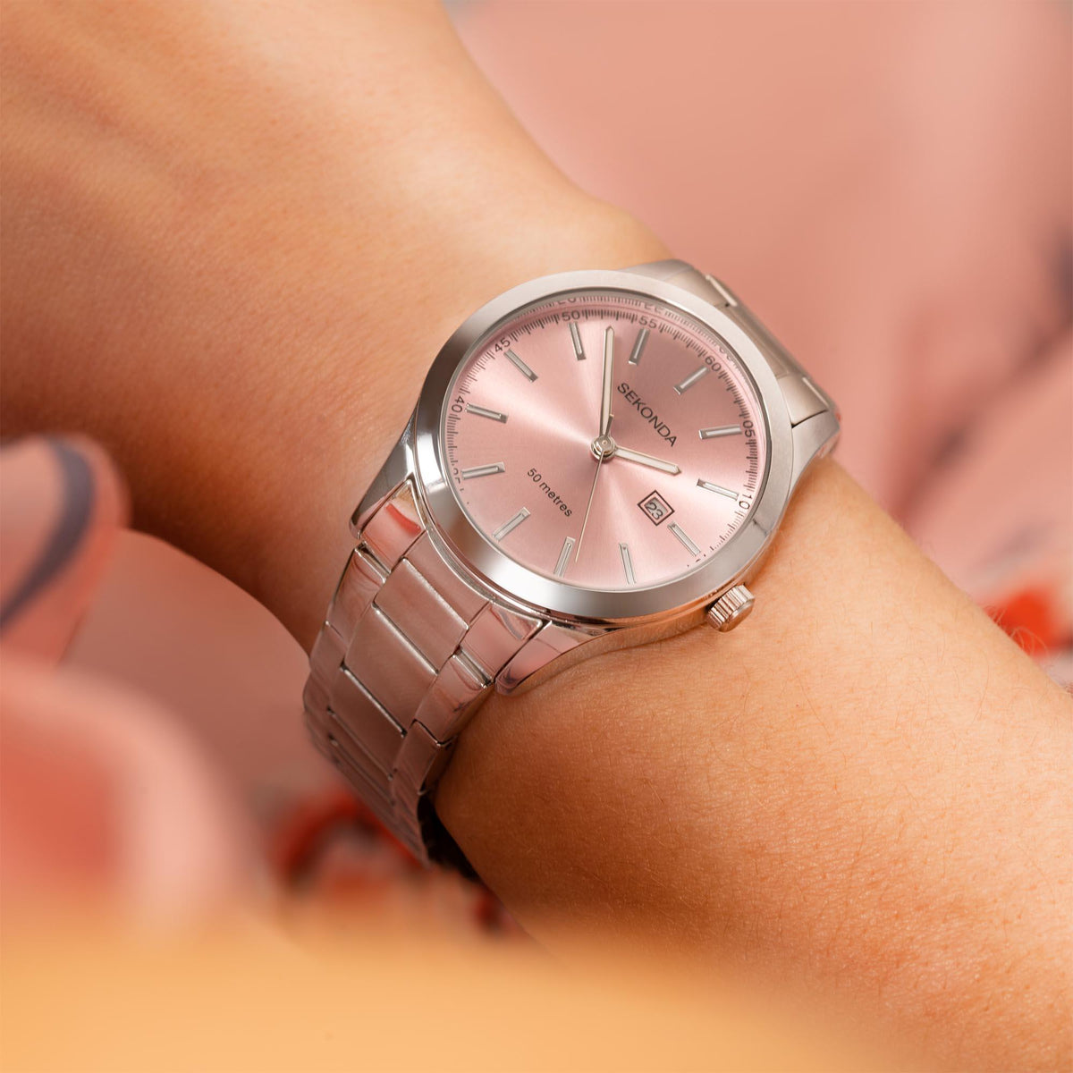 Ladies stainless steel bracelet watch on wrist with pink dial and silver hands