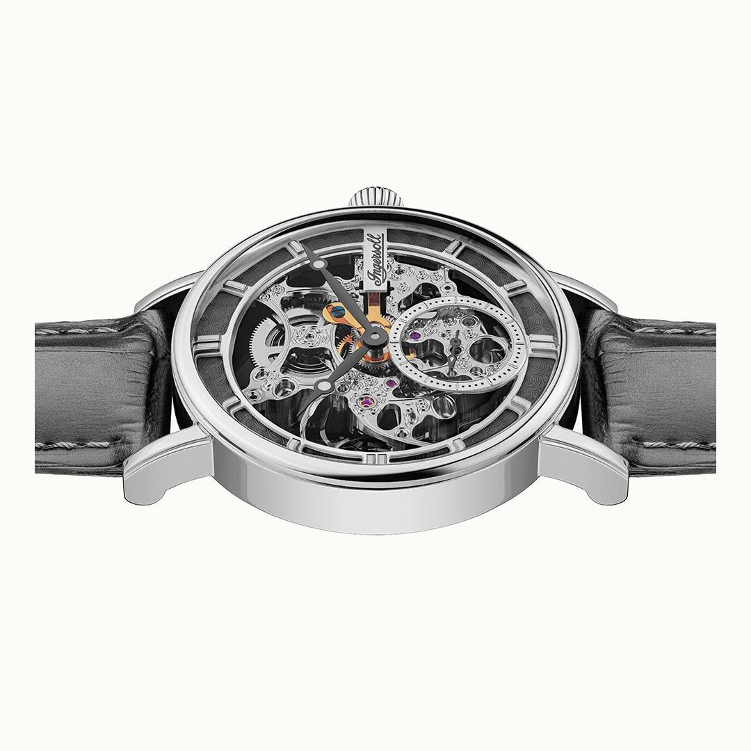 Center close-up of skeleton watch movement with jeweled gears and orange accent hand