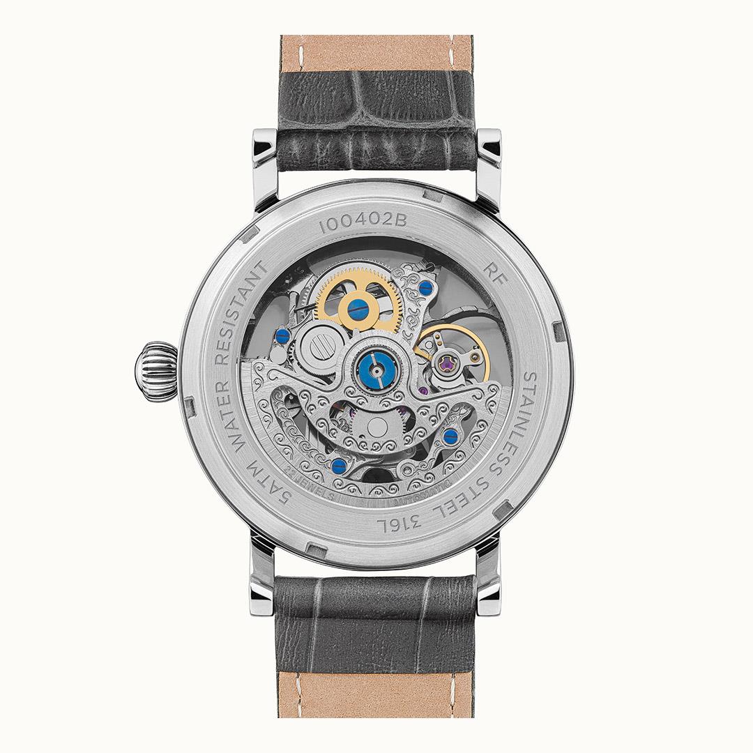 Caseback view of automatic skeleton watch with grey leather strap and blue jeweled parts