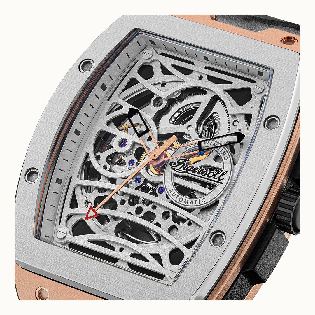 Close-up of skeleton watch movement behind clear window with black and rose-gold details.