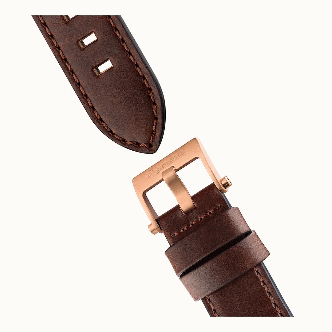 Brown leather watch strap with stitched edge and rose-gold clasp, angled close view.