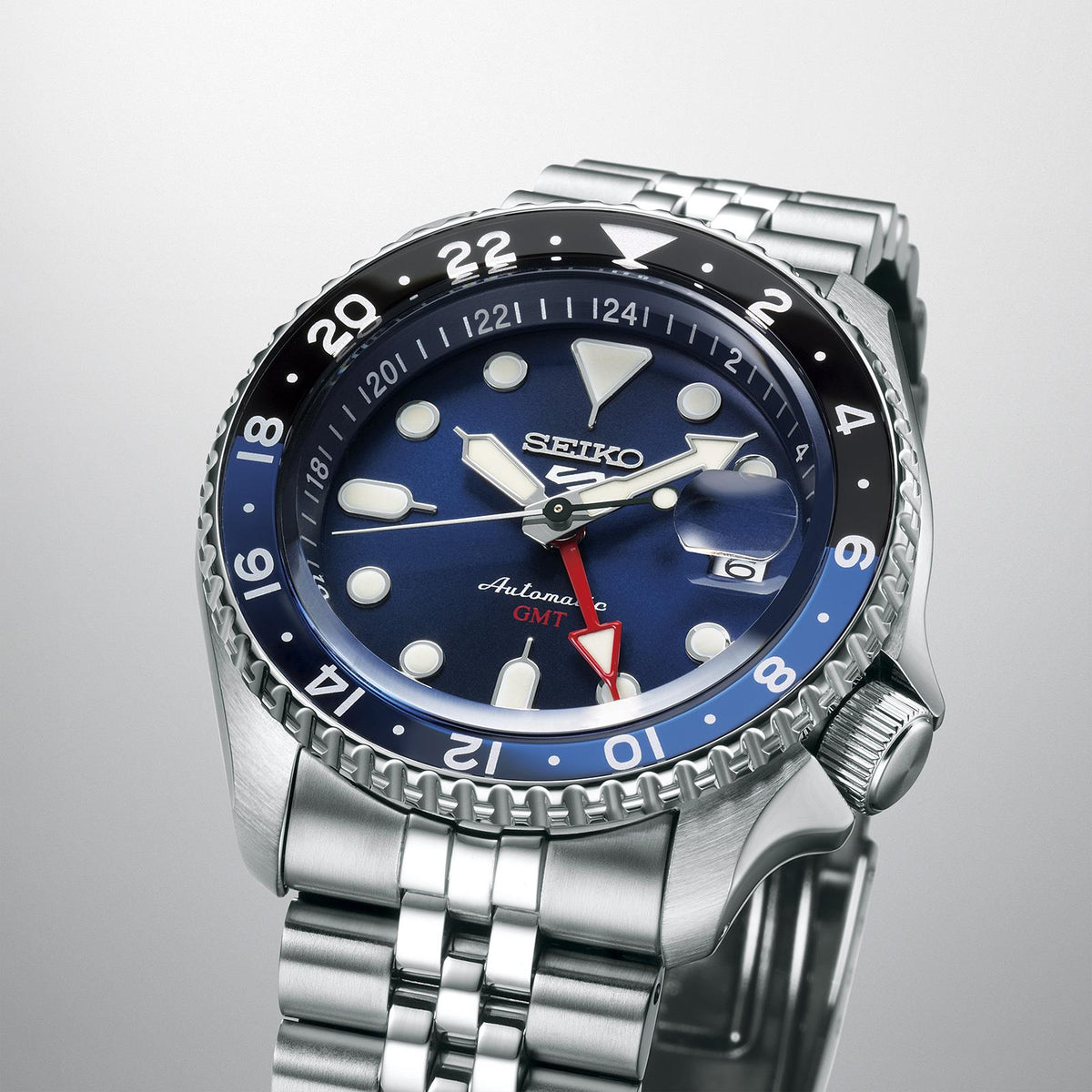 Close-up stainless steel GMT automatic watch with blue dial, red accents, and crown