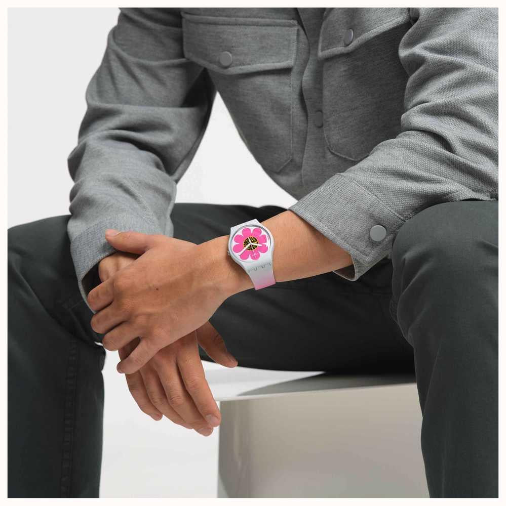 Pink flower dial silicone watch worn on wrist with dark pants and jacket sleeves