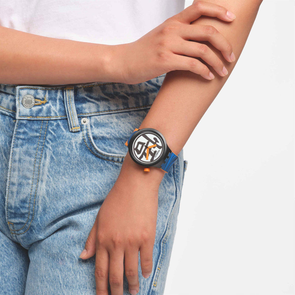 Person wearing a watch with a blue strap on a plain background