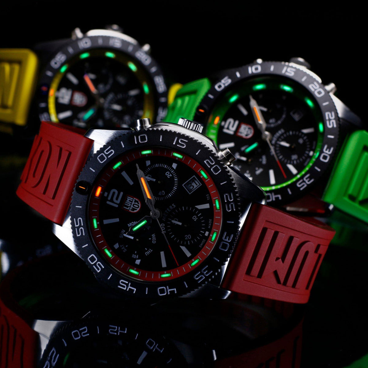 Two diver chronograph watches with red and green rubber straps, both with black dials.