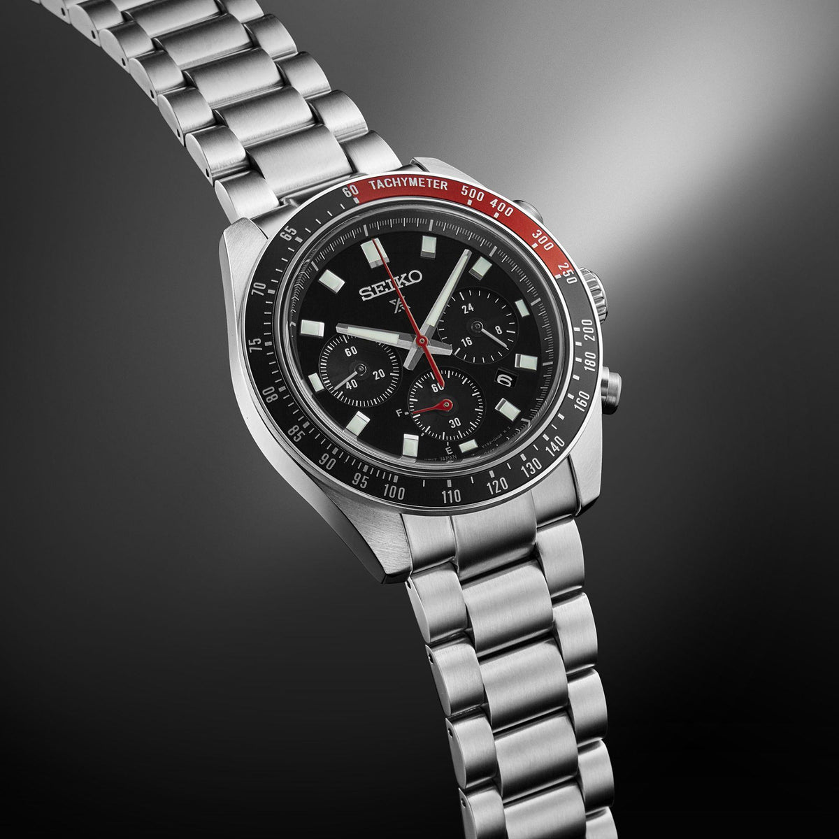 Men's stainless steel chronograph watch, side angled; black dial with tachymeter bezel markings.