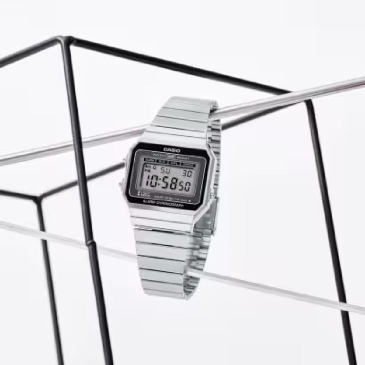 Silver metal bracelet digital alarm chronograph watch on stand, angled view with LCD display