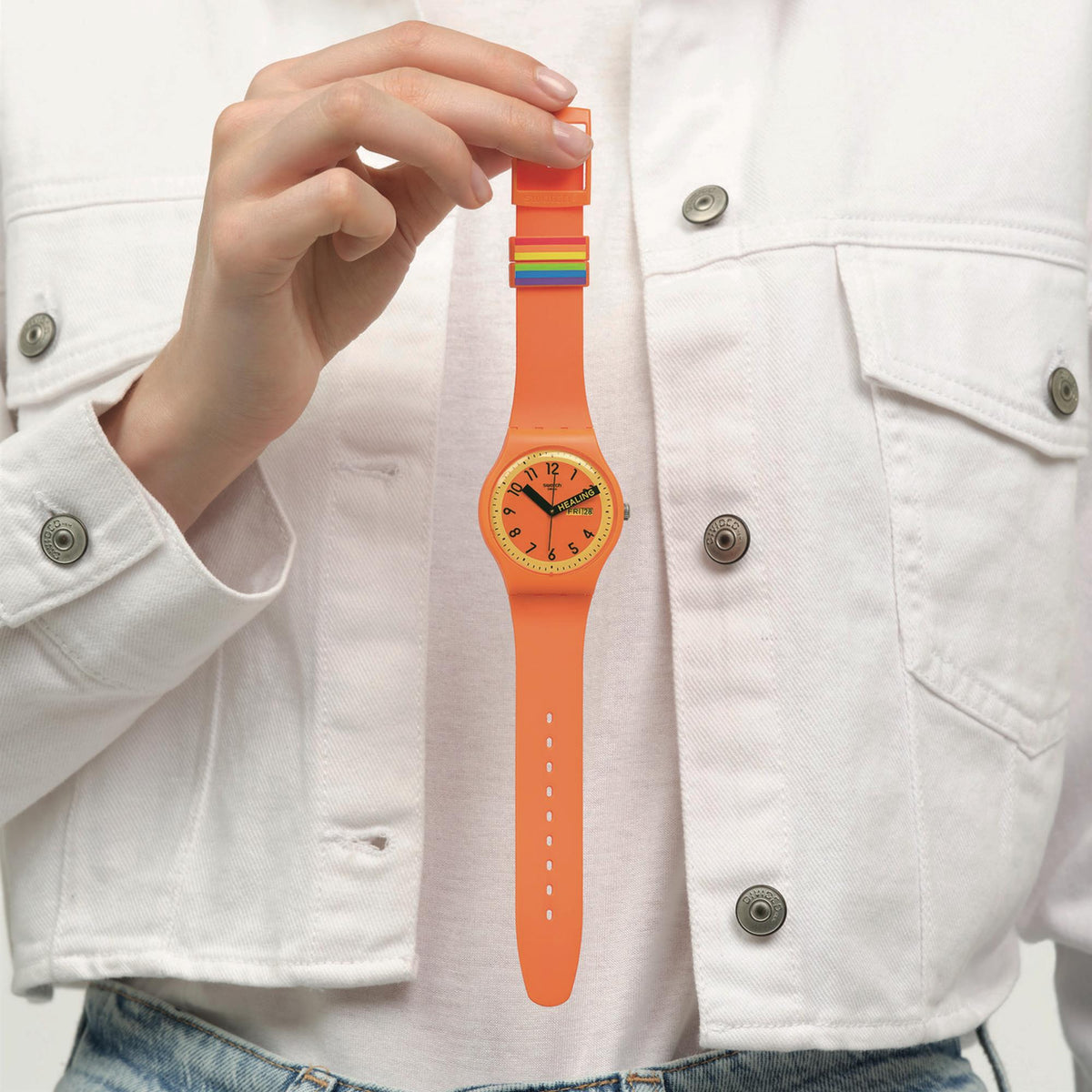 Orange quartz watch worn on wrist; hand lifts strap buckle