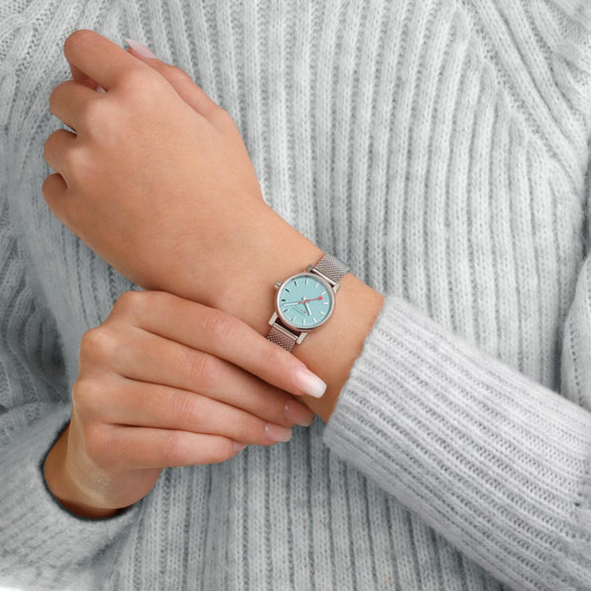 Watch on wrist with light blue dial and silver mesh band