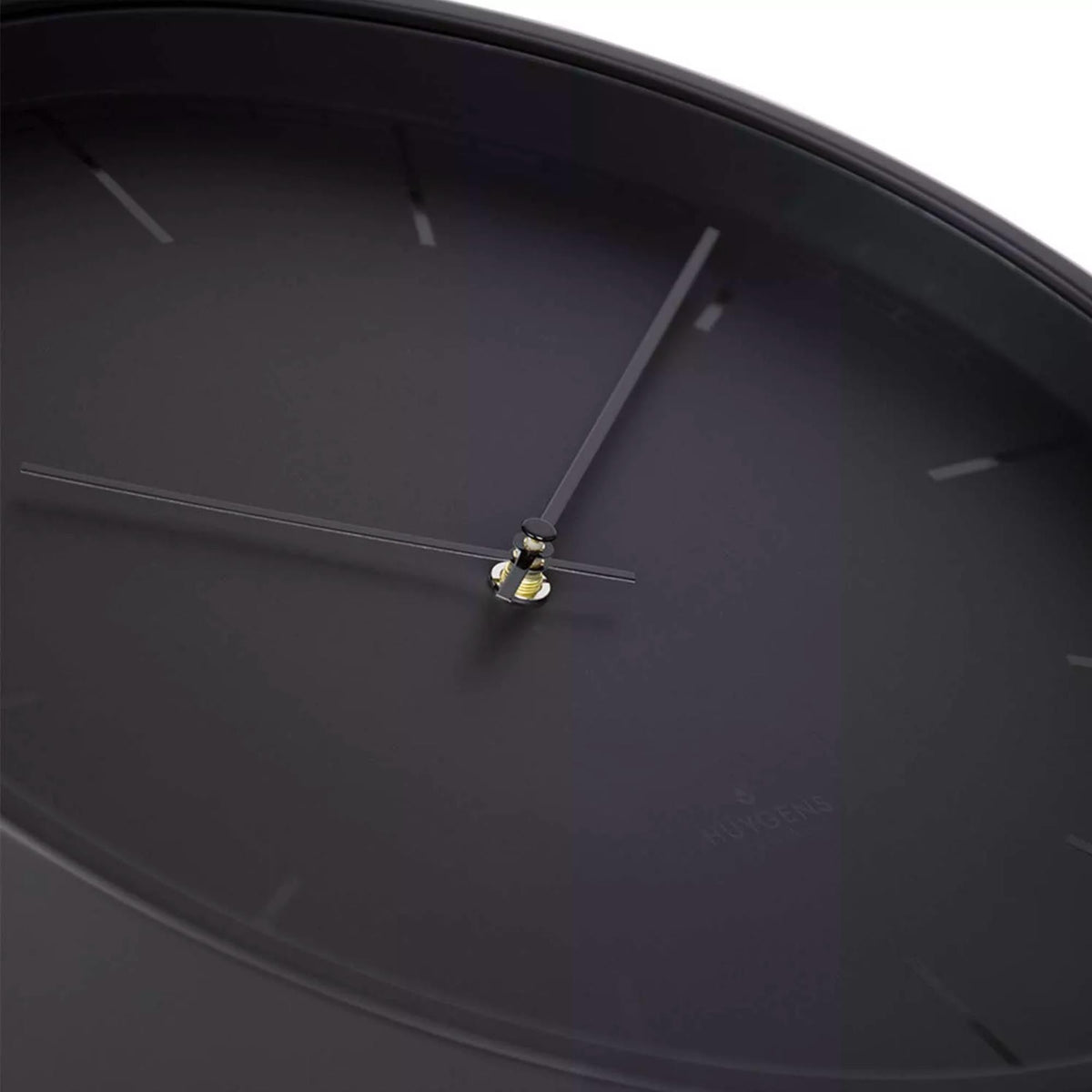 Close-up of black clock dial: slim hands meeting at center with index markers